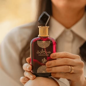 Person holding a red and black perfume bottle with intricate design