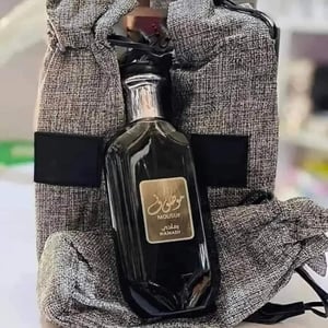 Bottle of Mousf with a gold label held by a person wearing a textured garment.