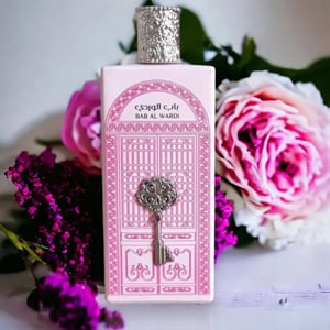 Bottle of Baa Al Wardi perfume with decorative box and flowers in the background