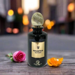 Perfume bottle labeled 'Mountain Nuit Paris' with flowers on a wooden surface