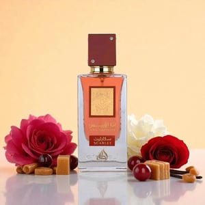 Perfume bottle labeled 'Scarlet' with flowers and candies on a reflective surface
