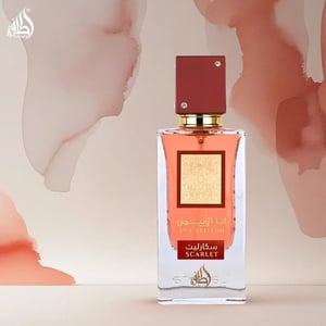 Perfume bottle with red cap and gold accents on a soft pink background