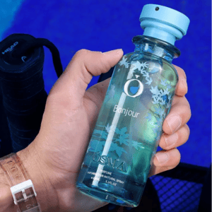 Hand holding a blue bottle labeled 'Bonjour' against a blue background