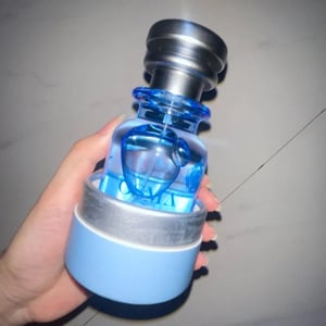 Blue and silver bottle with a hand holding it against a gray background