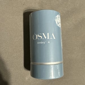 Blue cylindrical container with 'OSMA' branding on a beige background