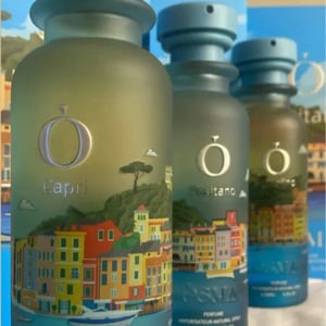 Three Osma perfume bottles with colorful labels on a blue background