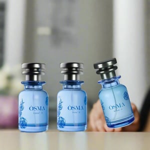 Three blue perfume bottles with silver caps on a reflective surface against a light blue background.