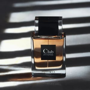 Perfume bottle labeled 'Club Intense' by Pendora on a dark surface with shadow patterns.