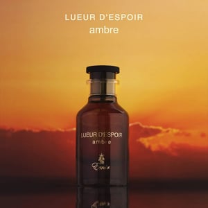 Bottle of Lueur d'Espoir Ambre perfume with a sunset background