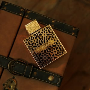 rayhaan elixir perfume bottle with intricate design on a brown leather surface