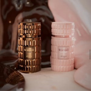 Two perfume bottles, one gold and one pink, with 'tiramisu' branding on a blurred background.